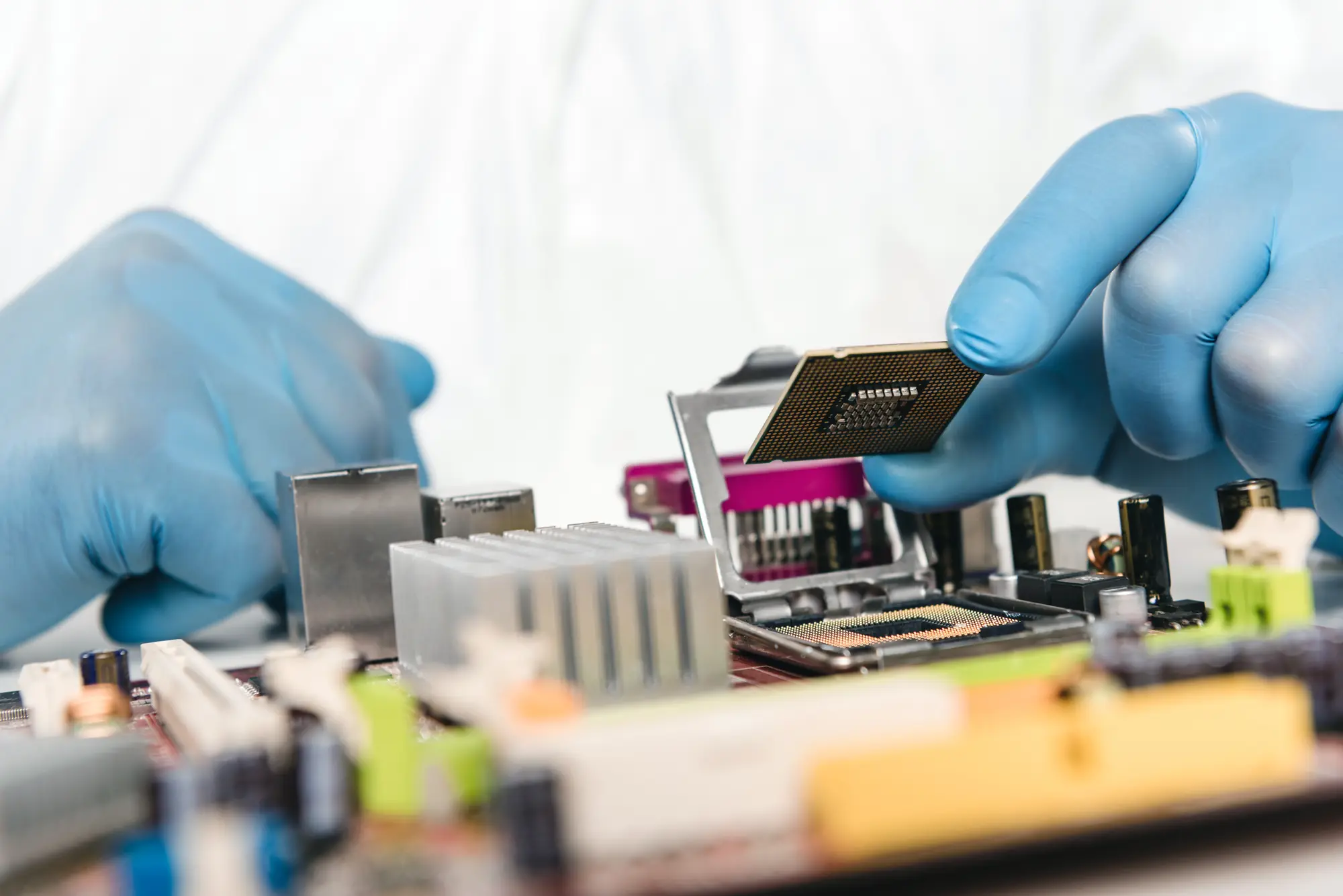 Gloved hands positioning an electronic component on a circuit board.