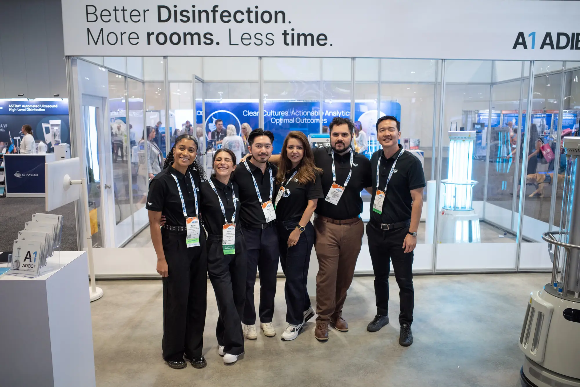 Six team members posing together in front of the TGR exhibition booth.