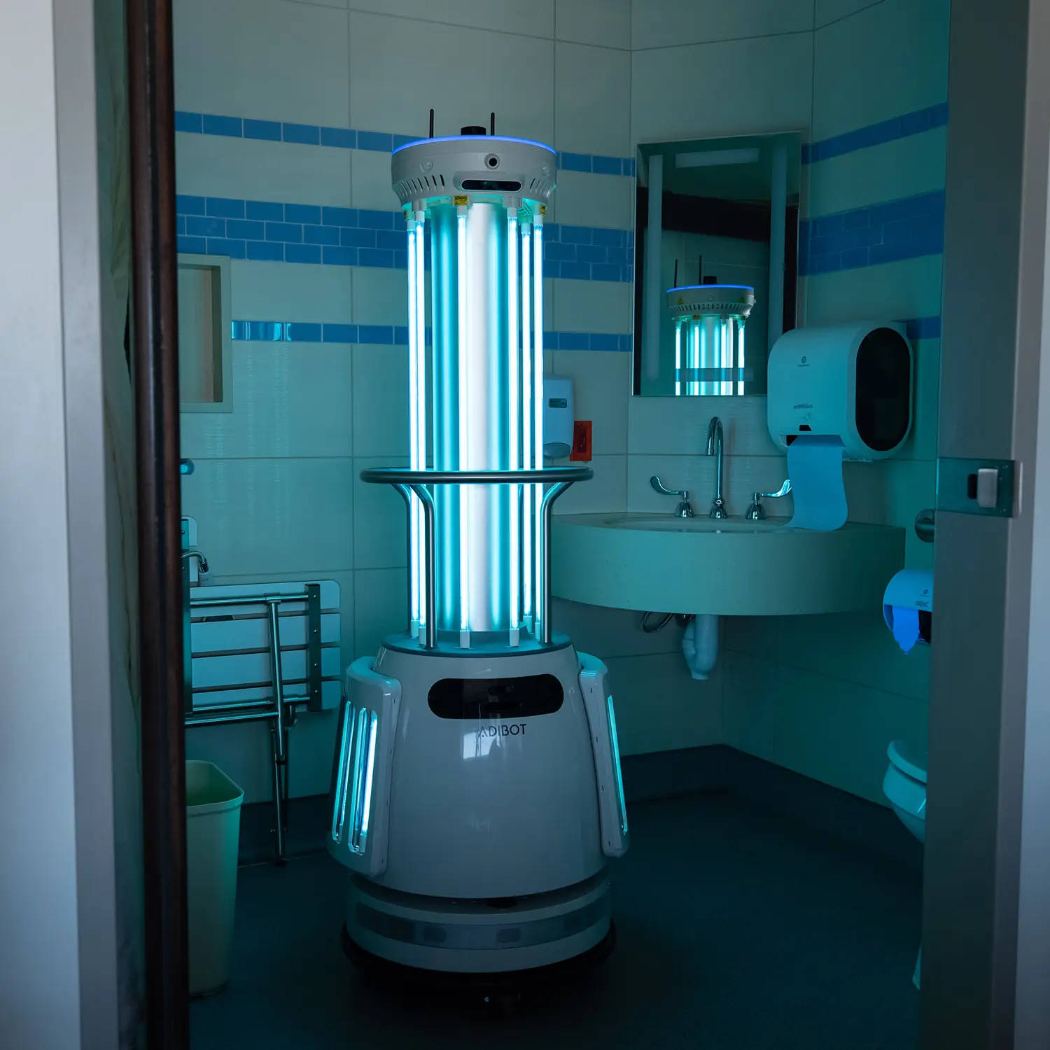 A1 robot with illuminated vertical UV-C lamps in an unoccupied room.