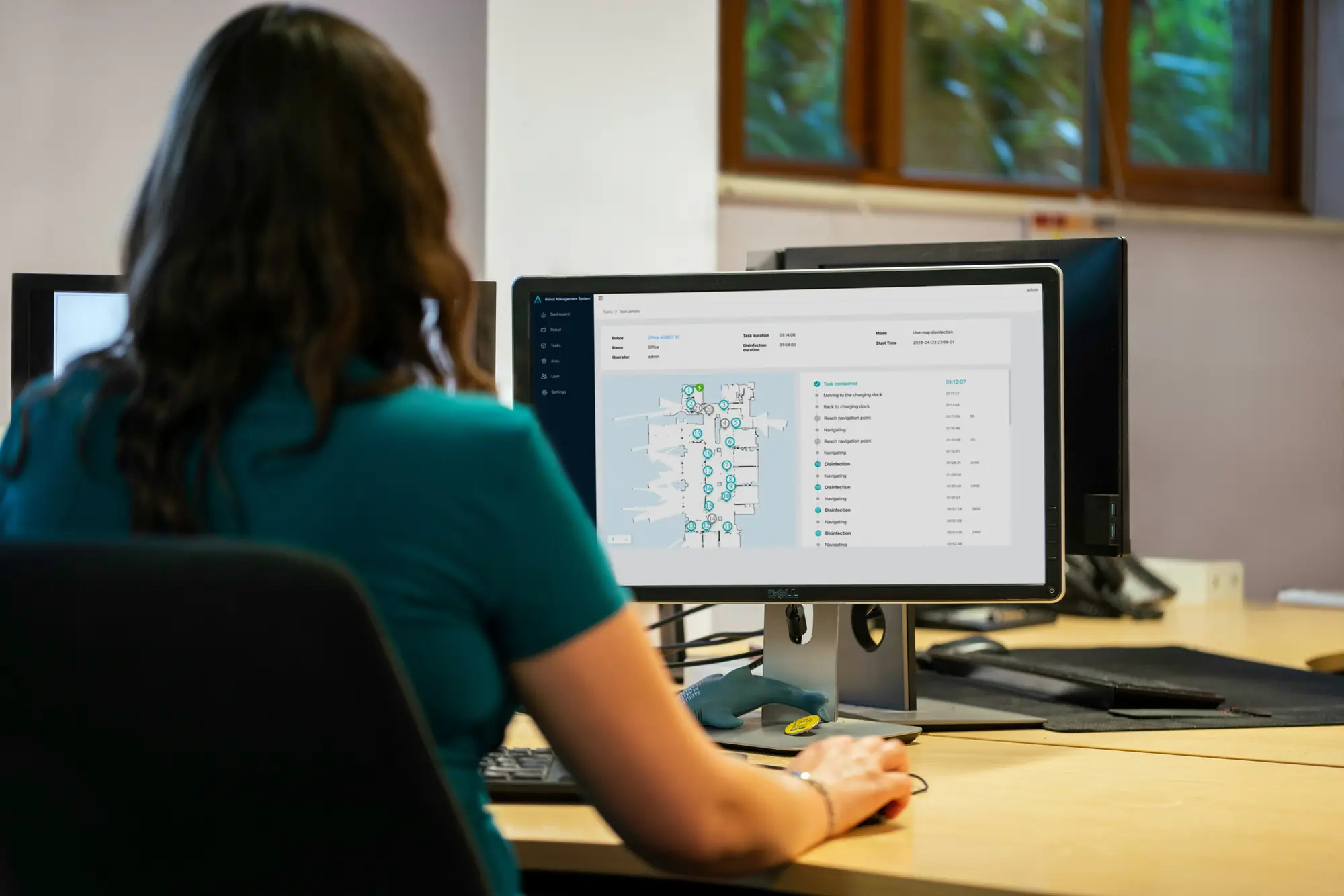 An operator reviewing a room map and task information on a desktop monitor.